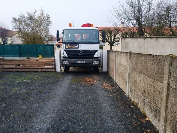 Camion TerraTed stationné sur une cour empierrée entre deux murs