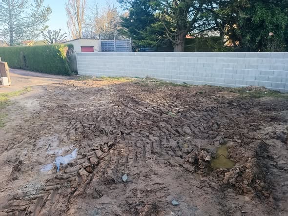 Terrain détrempé entre deux murs avant le terrassement d'une piscine