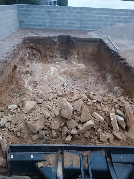 Fouille de piscine creusée dans le rocher, godet au premier plan