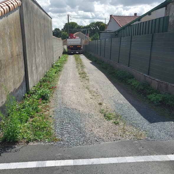 Accès étroit entre un mur et une clôture avant travaux, camion benne en fond