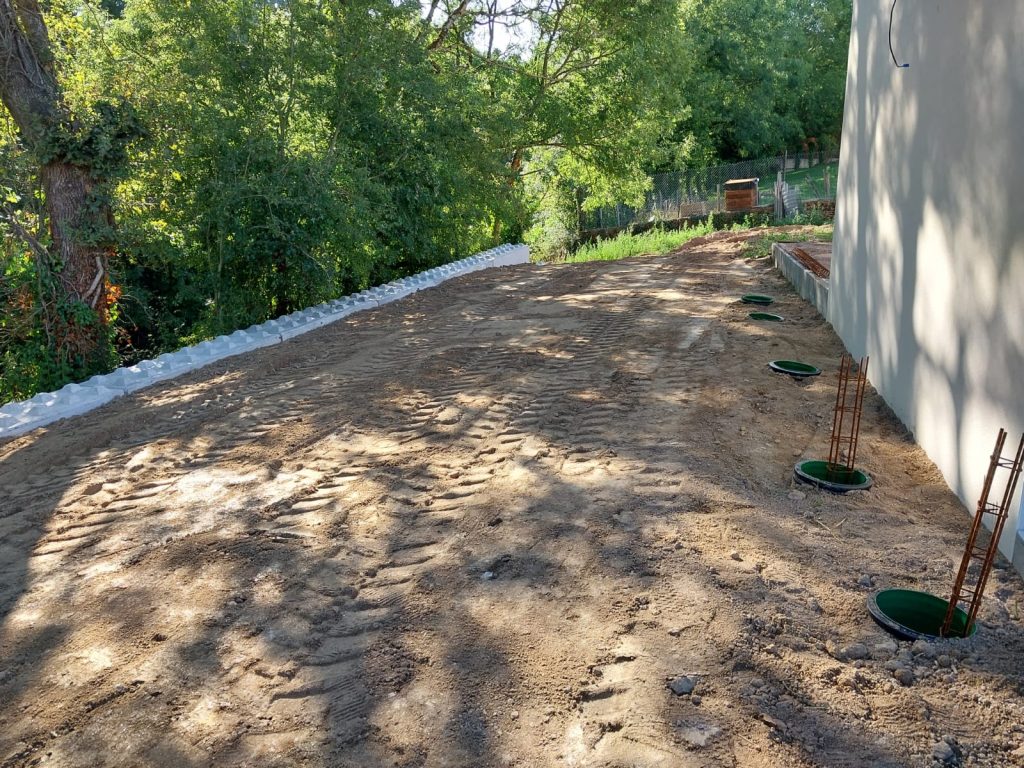 Plateforme nivelée le long d'une maison neuve, bordée de blocs béton