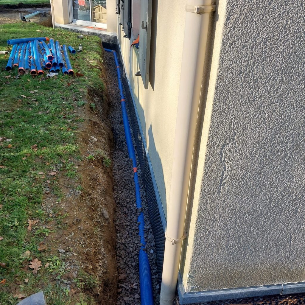Tuyau de drainage posé sur lit de gravier en pied de mur, à Beaurepaire