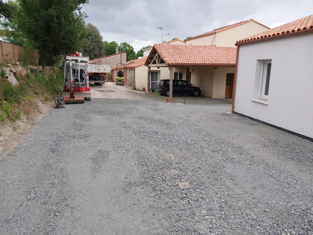 Cour empierrée après travaux d'assainissement, mini-pelle en fond