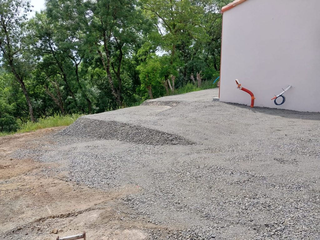 Terrain remis au propre en gravier autour d'une maison neuve après assainissement