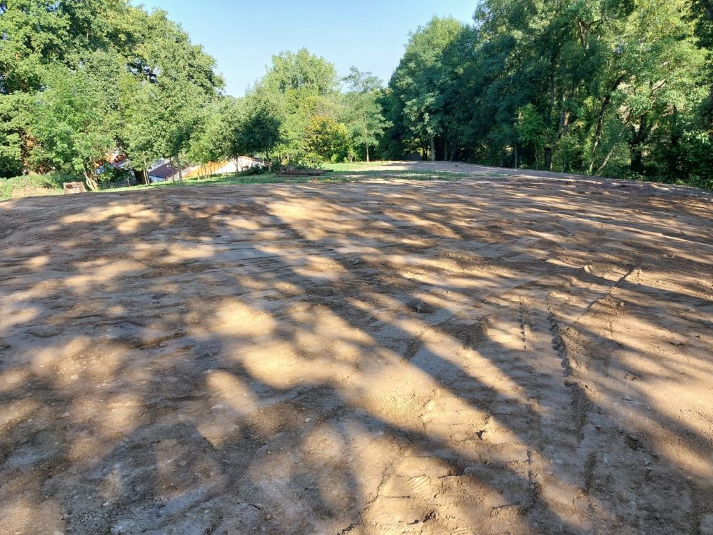 Terrain nivelé sous les arbres, prêt pour un aménagement extérieur