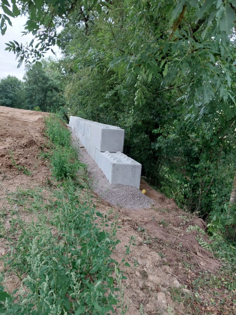 Blocs béton empilables posés en soutènement au bord d'un talus boisé