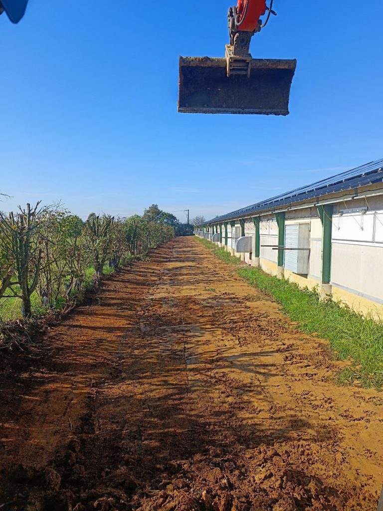 Tranchée remblayée et terrain nivelé le long d'un bâtiment agricole