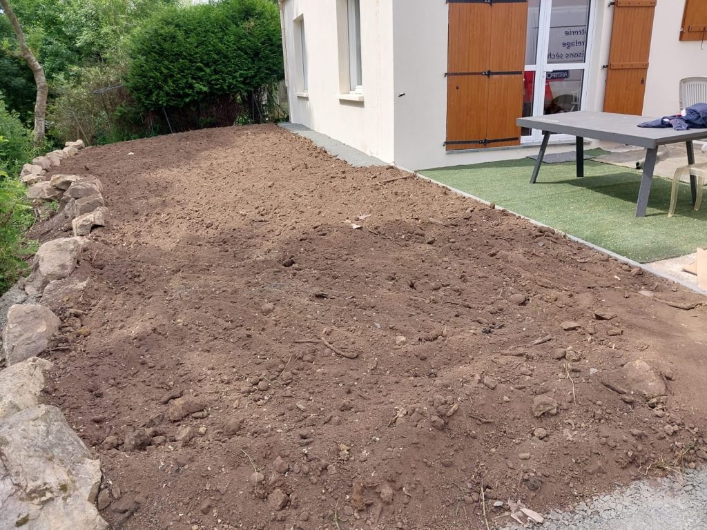 Terre régalée et nivelée en bordure de terrasse après des travaux d'assainissement